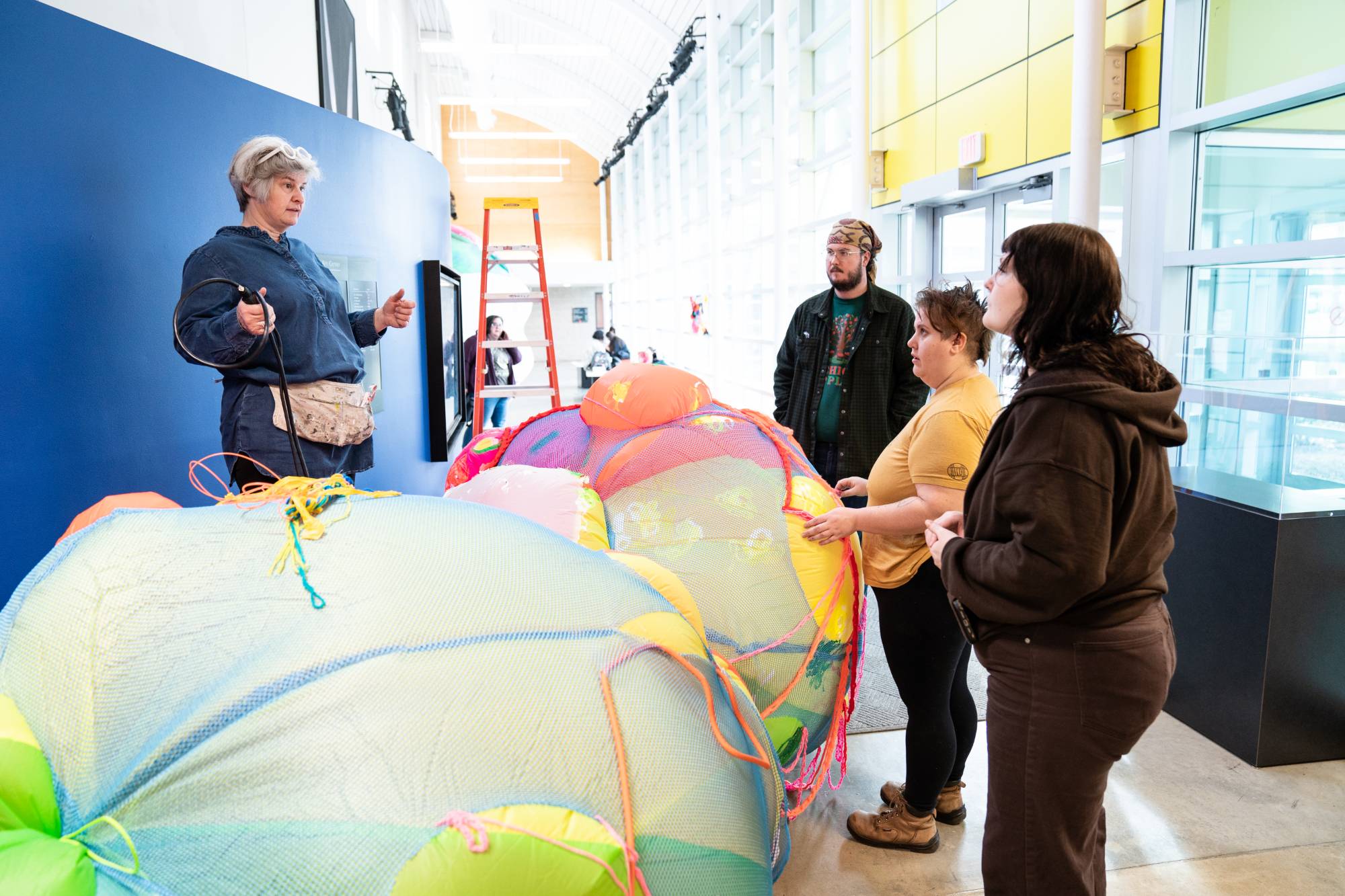Brightly colored ball shaped sculpture being installed by group of students & artist Claire Ashley.